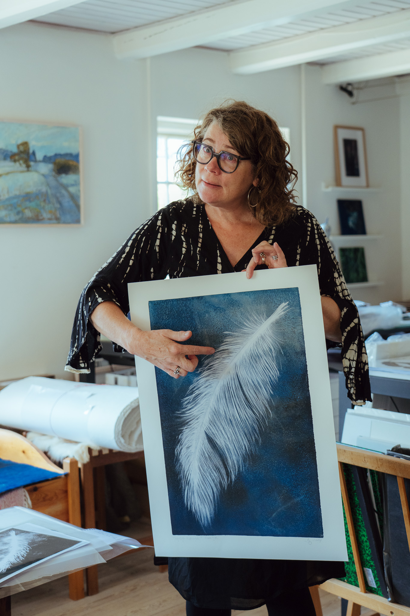 Karin Lykke fremviser og fortæller om et tryk med en hvid fjer på
