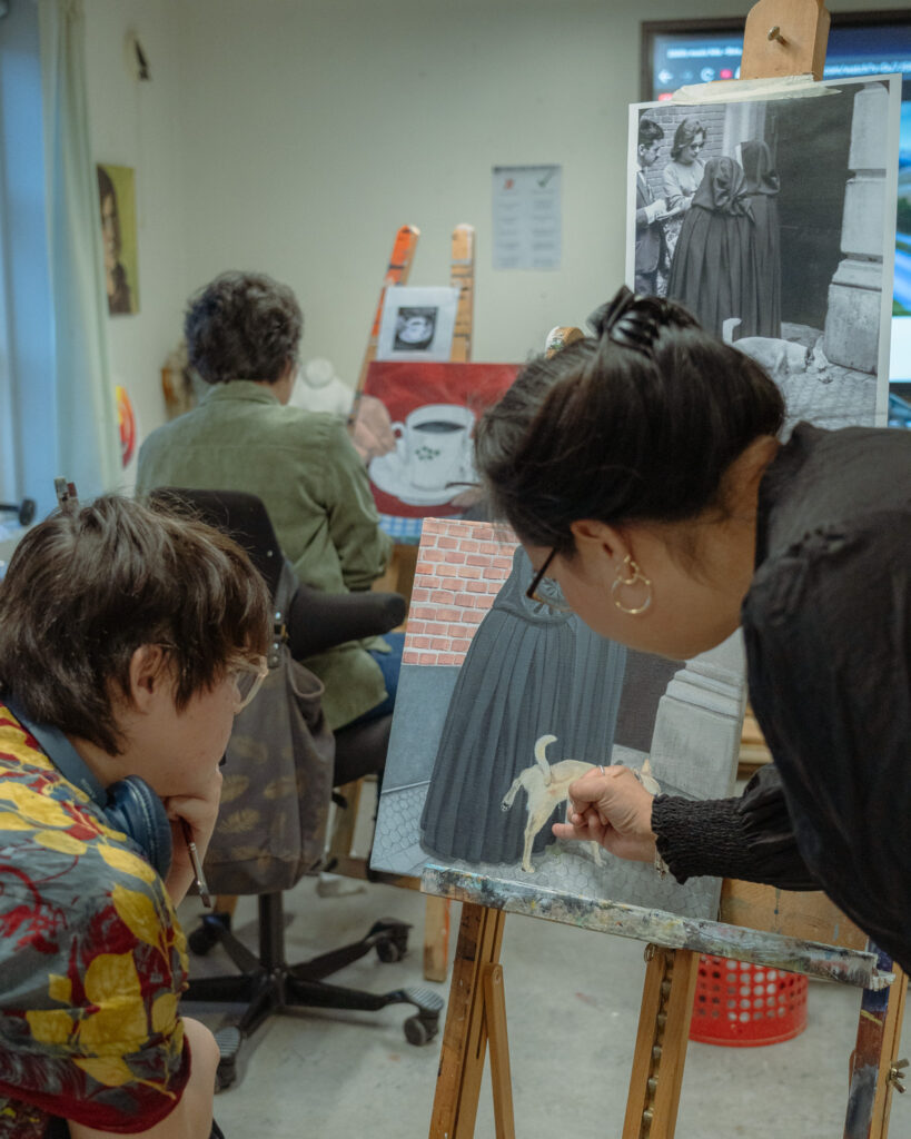 Billede af Ivinguak der giver feedback til en elev der er i gang med at male